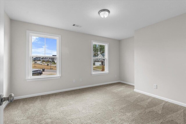 empty room with plenty of natural light, carpet floors, and visible vents