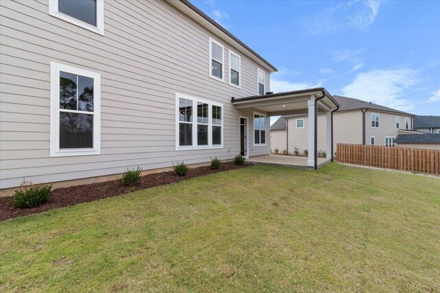 back of property featuring a patio, a lawn, and fence