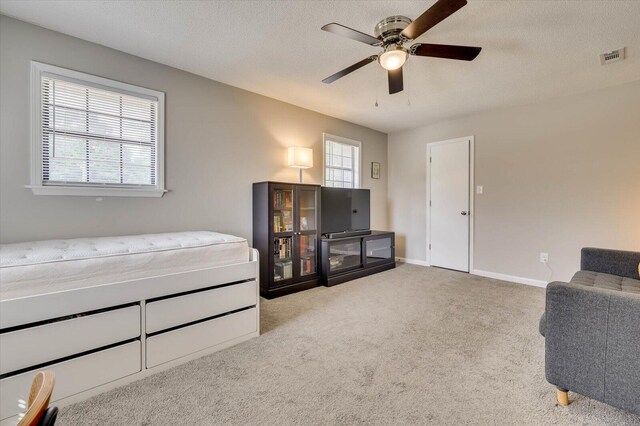 interior space featuring a textured ceiling, ceiling fan, and light carpet