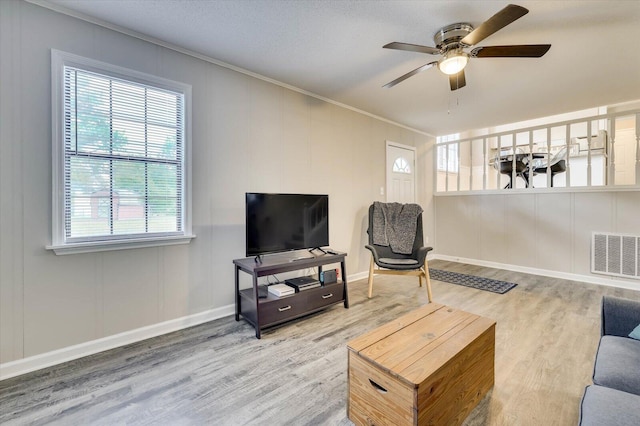 living room with ceiling fan, wood-type flooring, and crown molding