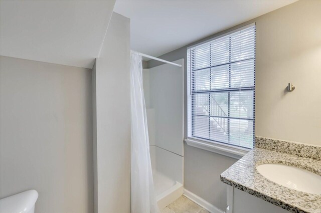 bathroom featuring toilet, plenty of natural light, vanity, and walk in shower