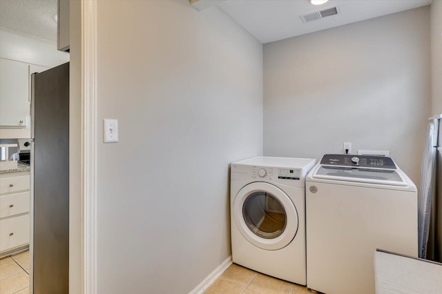 laundry area featuring light tile patterned floors, washing machine and dryer, and a textured ceiling