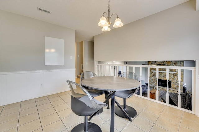 tiled dining room featuring lofted ceiling, a fireplace, and a chandelier