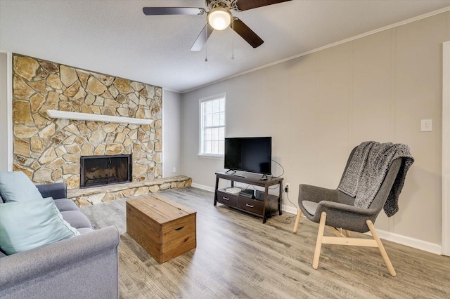 living room featuring ceiling fan, a fireplace, hardwood / wood-style flooring, and ornamental molding