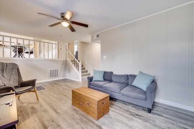 living room with ceiling fan, wood-type flooring, and ornamental molding