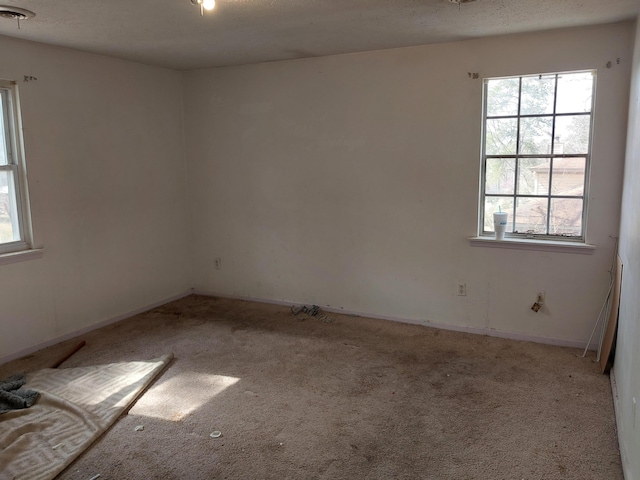 carpeted empty room with a wealth of natural light, visible vents, and a textured ceiling