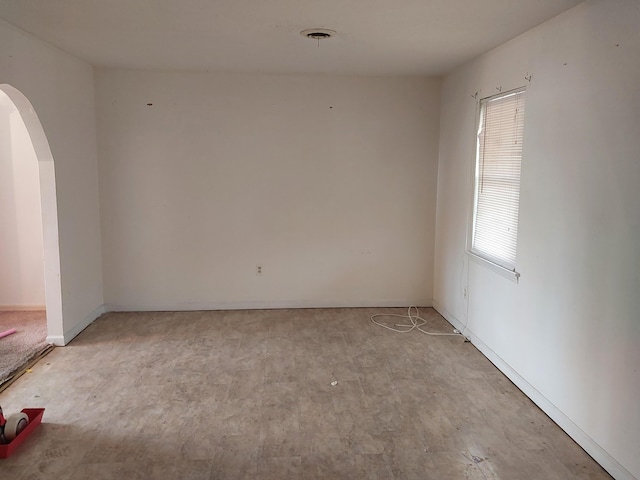 unfurnished room with arched walkways and light wood-style flooring