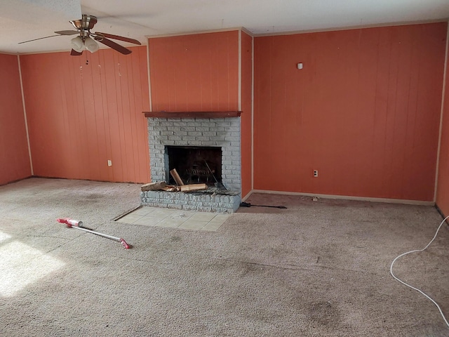 unfurnished living room featuring wooden walls, carpet flooring, a fireplace, and ceiling fan