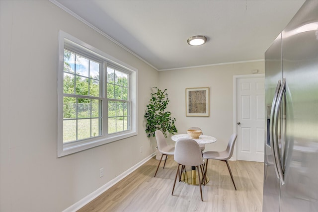 dining room featuring crown molding, baseboards, and light wood-style flooring