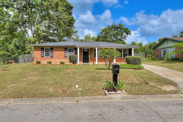 ranch-style home with concrete driveway, brick siding, fence, and a front lawn