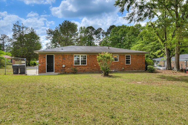back of property featuring brick siding, fence, and a yard