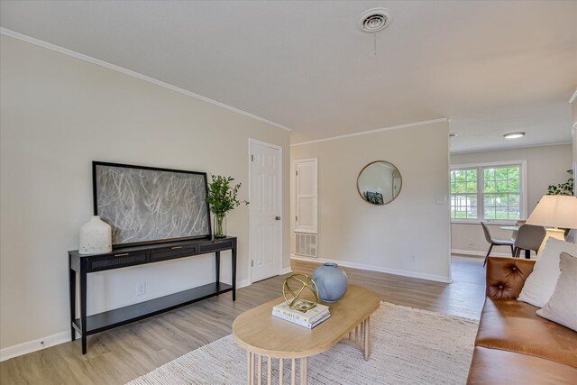 living room featuring baseboards, ornamental molding, wood finished floors, and visible vents