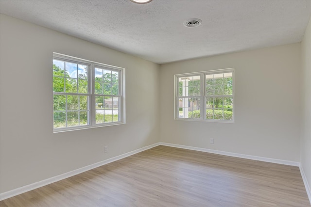 unfurnished room featuring visible vents, baseboards, wood finished floors, and a healthy amount of sunlight