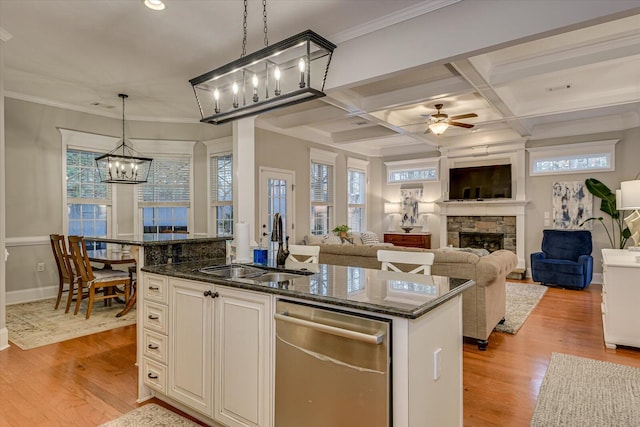 kitchen featuring coffered ceiling, a kitchen island with sink, sink, pendant lighting, and a stone fireplace