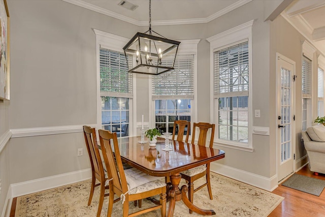 dining area featuring light wood-type flooring, a notable chandelier, and ornamental molding