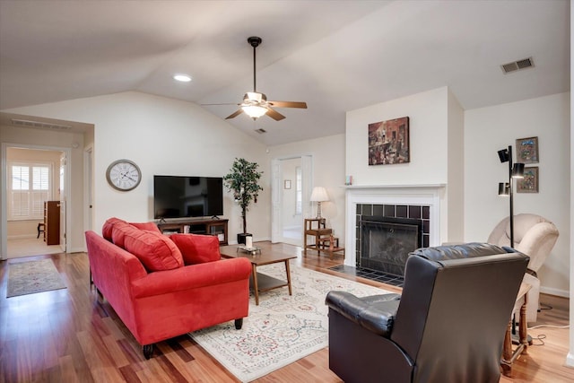 living room featuring ceiling fan, wood-type flooring, a fireplace, and vaulted ceiling