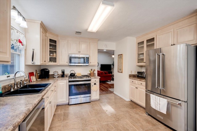 kitchen featuring appliances with stainless steel finishes, a textured ceiling, sink, light tile patterned floors, and hanging light fixtures