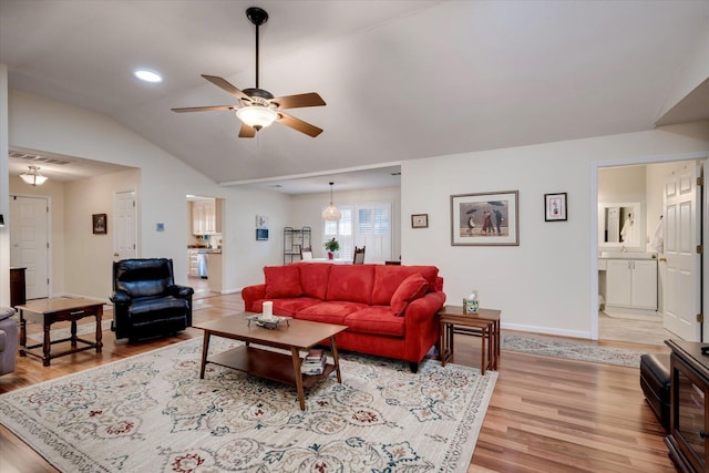 living room featuring ceiling fan, light hardwood / wood-style floors, and vaulted ceiling