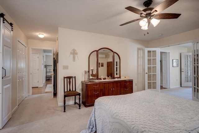 carpeted bedroom with ceiling fan, a barn door, and french doors