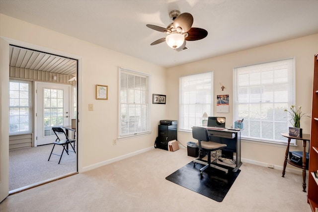 home office with a wealth of natural light, ceiling fan, and carpet floors