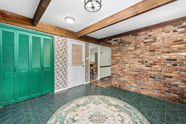 2216 Silverdale Rd, Augusta, GA 30906 - foyer entrance featuring beamed ceiling, dark tile patterned flooring, brick wall, and a textured ceiling