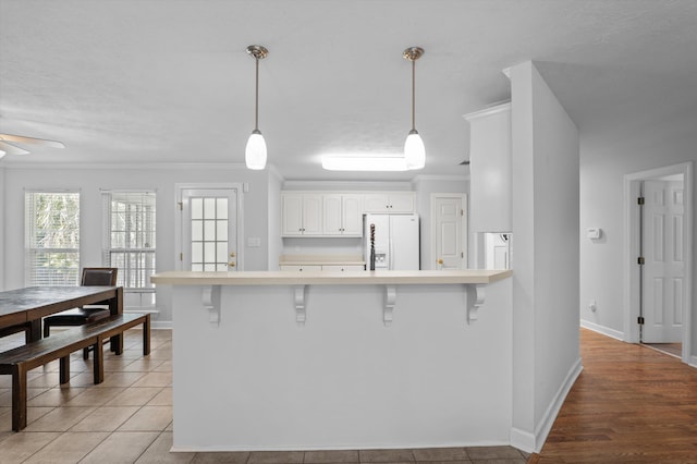 1382 Shadow Oak Dr, Evans, GA 30809 - kitchen featuring white fridge with ice dispenser, a breakfast bar, a peninsula, light countertops, and crown molding