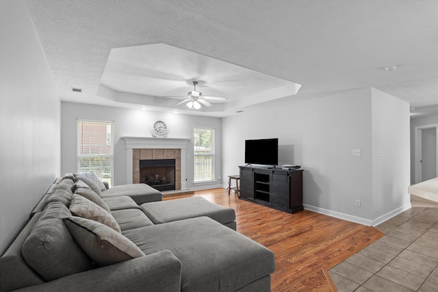 1382 Shadow Oak Dr, Evans, GA 30809 - living room with a tray ceiling, ceiling fan, baseboards, light wood-style floors, and a textured ceiling