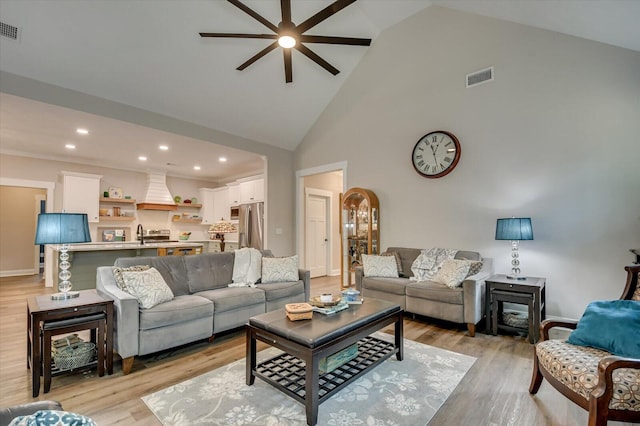 living room with light wood-type flooring, high vaulted ceiling, ceiling fan, and sink