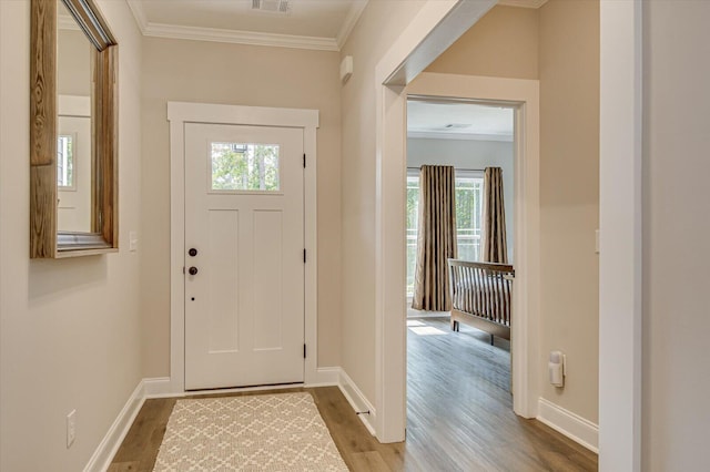 foyer entrance featuring hardwood / wood-style flooring, a wealth of natural light, and ornamental molding