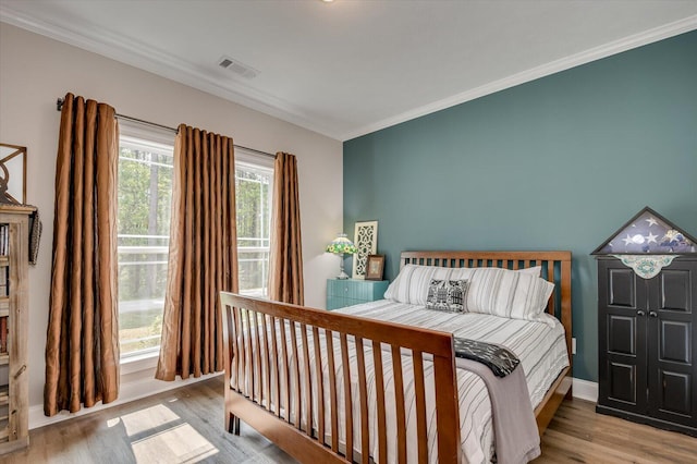 bedroom featuring light hardwood / wood-style flooring and crown molding