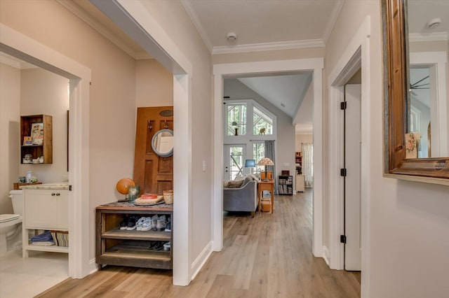 hall with light hardwood / wood-style floors, crown molding, and lofted ceiling