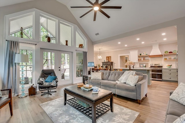 living room with french doors, light hardwood / wood-style flooring, high vaulted ceiling, and ceiling fan with notable chandelier