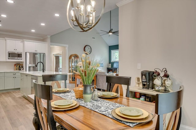 dining space featuring ceiling fan with notable chandelier, light wood-type flooring, ornamental molding, and sink