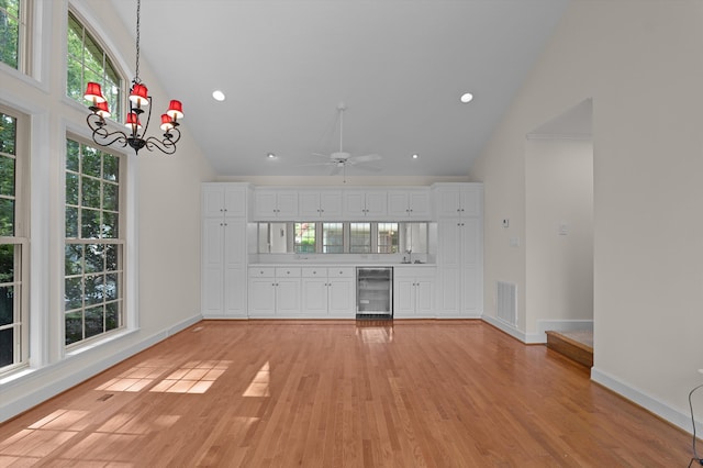 3076 Westwood Rd, Augusta, GA 30909 - unfurnished living room with high vaulted ceiling, beverage cooler, light wood-style floors, a chandelier, and ceiling fan