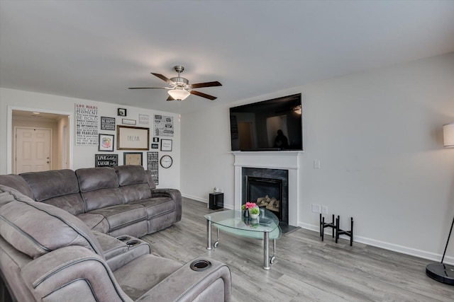 living room featuring a fireplace, light wood-type flooring, and ceiling fan