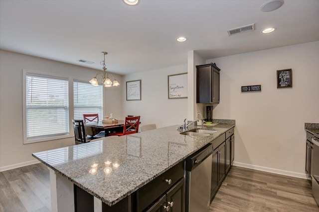 kitchen featuring light stone countertops, kitchen peninsula, sink, dishwasher, and a chandelier