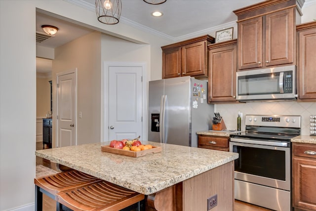 867 Williford Run Dr, Grovetown, GA 30813 - kitchen with appliances with stainless steel finishes, a kitchen bar, light stone counters, ornamental molding, and decorative backsplash