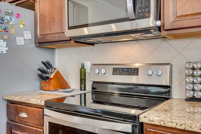 867 Williford Run Dr, Grovetown, GA 30813 - kitchen featuring appliances with stainless steel finishes, decorative backsplash, brown cabinets, and light stone counters