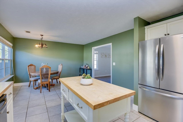 kitchen featuring white cabinetry, a center island, wooden counters, decorative light fixtures, and appliances with stainless steel finishes