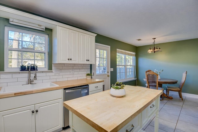 kitchen featuring butcher block counters, white cabinetry, sink, stainless steel dishwasher, and pendant lighting