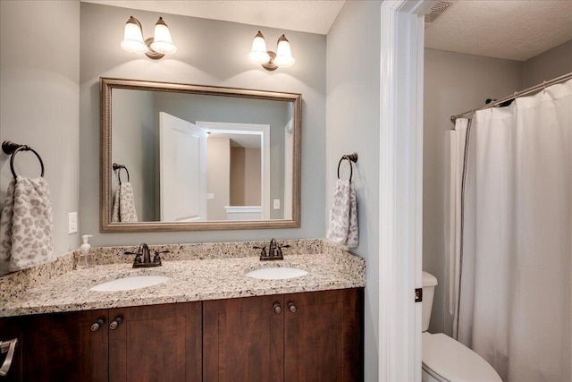 full bathroom with double vanity, toilet, and a sink