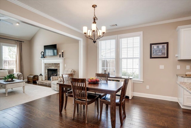 dining space featuring dark wood-style flooring, visible vents, a stone fireplace, and a healthy amount of sunlight