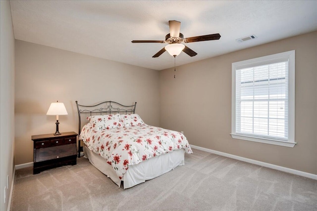 carpeted bedroom with a ceiling fan, visible vents, and baseboards