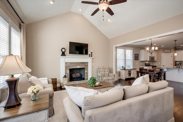 living area with ceiling fan with notable chandelier, a stone fireplace, wood finished floors, and recessed lighting