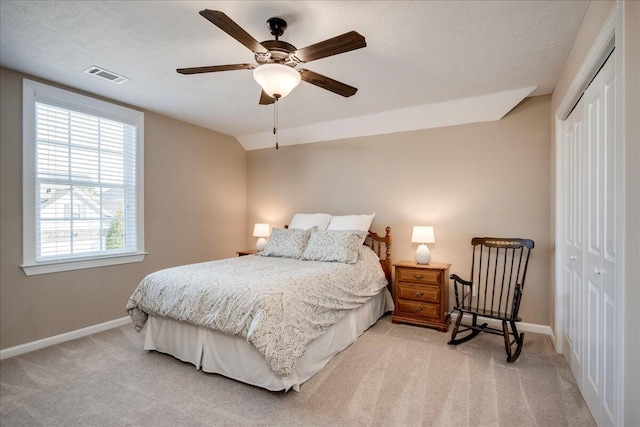 bedroom featuring lofted ceiling, a closet, visible vents, light carpet, and baseboards