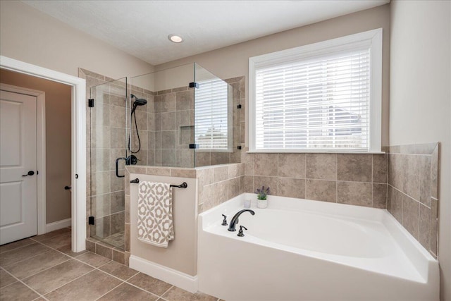 bathroom featuring tile patterned flooring, a garden tub, a shower stall, and baseboards