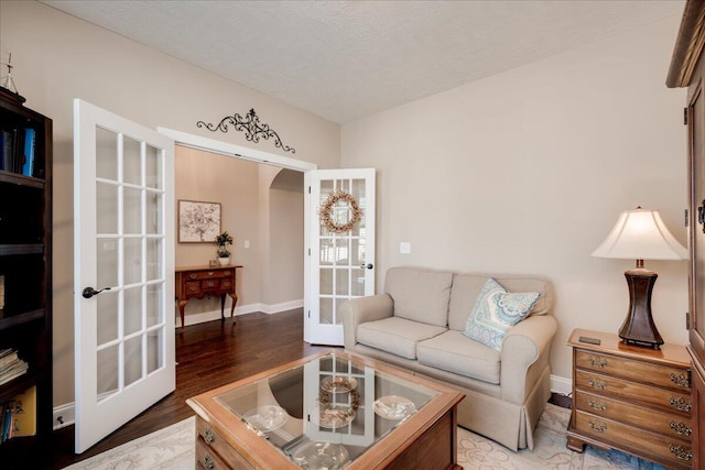 living area featuring a textured ceiling, french doors, light wood-style flooring, and baseboards