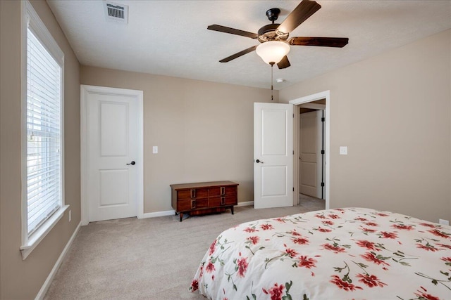 bedroom featuring baseboards, multiple windows, visible vents, and light colored carpet