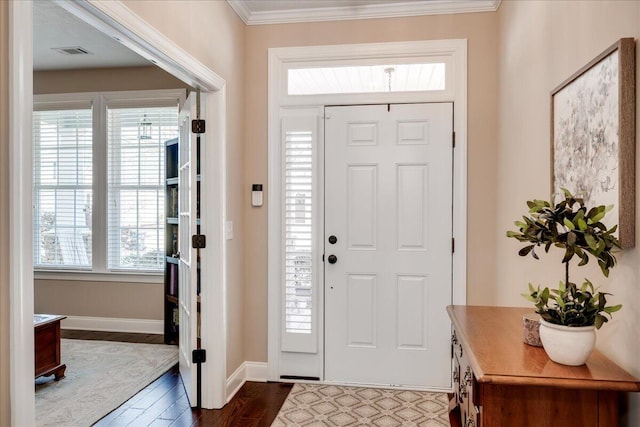 foyer with dark wood-style floors, visible vents, crown molding, and baseboards