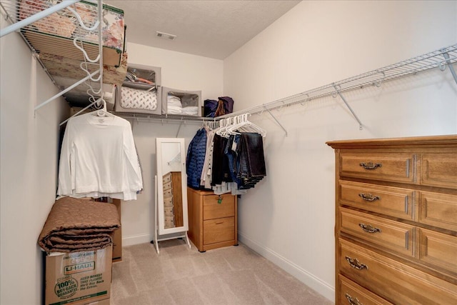 walk in closet with visible vents and light colored carpet